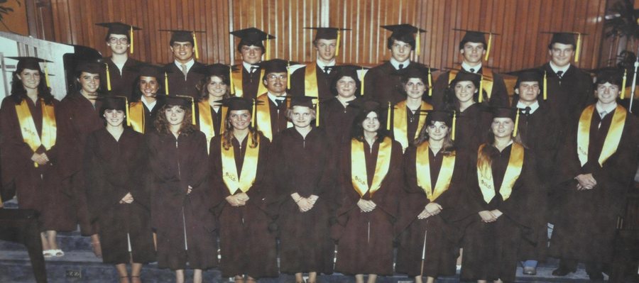 Historical group graduation photograph with graduates wearing caps and gowns.