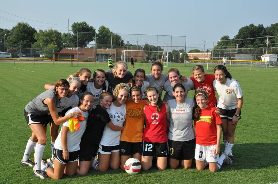 Soccer group posing together on an outdoor field.